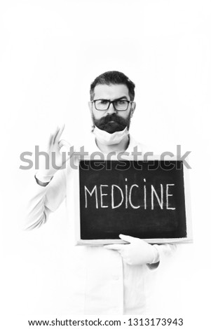 Bearded man, long beard. Brutal caucasian doctor or unshaven hipster, postgraduate student in mask, medical gown holding board isolated on white studio background. Medicine concept