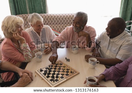 High angle view of group of senior people playing chess on table in living room at nursing home Royalty-Free Stock Photo #1313176163