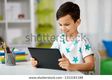 education, people and learning concept - happy student boy with tablet pc computer and notebook learning at home