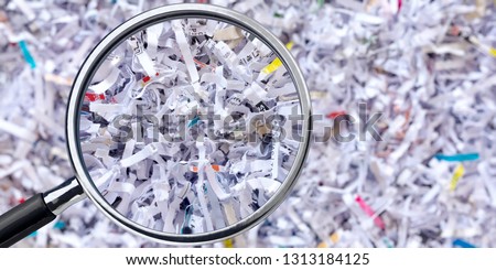 Shreeded document under the magnifying glass Royalty-Free Stock Photo #1313184125