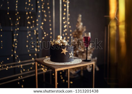 Young beautiful charismatic extraordinary girl woman in an elegant black dress in the image of the queen celebrates her birthday with a cake and candles, studio shooting, emotions, celebration, fun