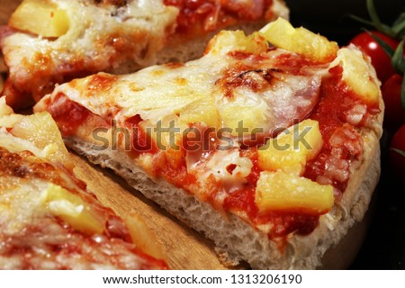 Delicious pizza with pineapple, ham slice, bacon slice, mozzarella cheese, pizza sauce on rustic background for fast food and ready to eat concept. pizza hawaii