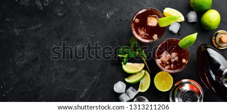 Alcoholic Beverage Rum, lime and mint on a black stone background. Top view. Free space for your text.