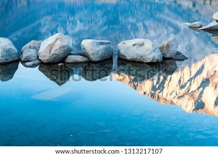 Detail abstract photo of rocks and the reflection of the Sierra Nevada mountains on a calm Convict Lake at sunrise in California