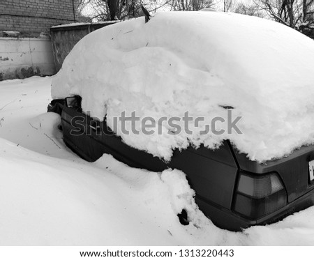fully snow-covered car stands in winter