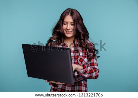 Portrait of an excited young girl holding laptop computer and celebrating success isolated over blue