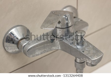 Close-up of shower mixer faucet with limescale, white chalky deposit and stains. Formed on the plumbing system by a combination of soap residues and hard water. Concept of cleaning limescale plumbing Royalty-Free Stock Photo #1313264408