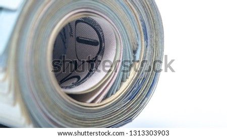 100 dollar bills twisted into tube and tied with an elastic band. white background.
