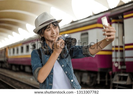 Happy young woman. girl with backpack taking photo with take a picture of yourself at train station landscape view and smile happily.
Backpacker concept, vintage train,blurred background