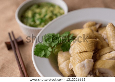 Cantonese style Poached Chicken, White cut chicken, cut, with ginger and spring onion sauce at the background