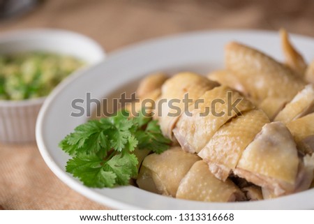 Cantonese style Poached Chicken, White cut chicken, cut, with ginger and spring onion sauce at the background