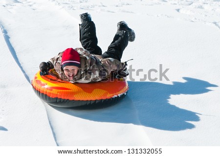 Happy boy sledding on a tube down a hill.