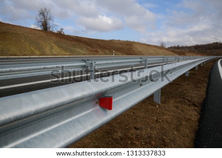 Steel guard rail barrier on the motorway with red reflective sign