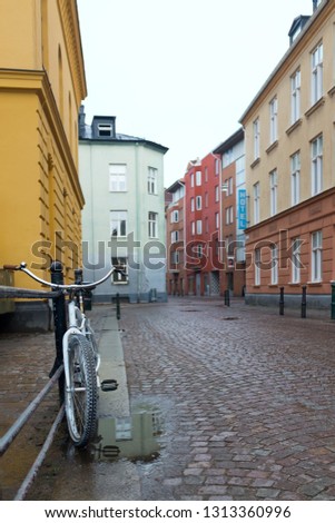 White bicycle chained to a rail in a cobblestone alley of colorful buildings