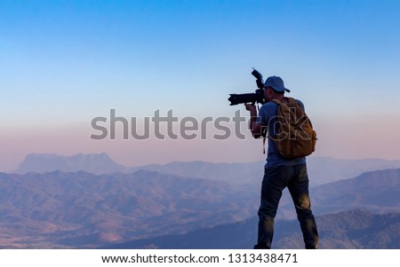 Nature photographer take photos with camera on top mountain Royalty-Free Stock Photo #1313438471