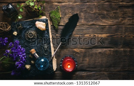 Spell book, magic potions and other various witchcraft accessories on the wizard table background with copy space. Royalty-Free Stock Photo #1313512067