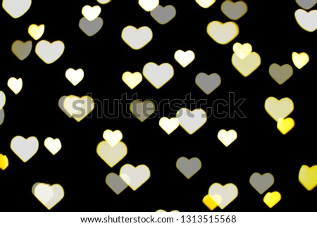 Beautiful yellow and white bokeh on a black background. Can be used as a background or wallpaper. Heart shape. Love Concept, Valentine's Day.
