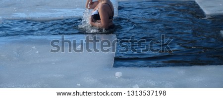 A woman bathes in an ice-hole in the winter in an icy water walrus