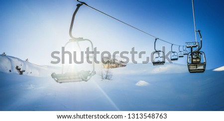 Panorama of ski lift and empty seats in the air on steel ropes at sunny winter day. 