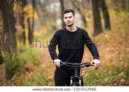Happy cyclist man ride on his bicycle on a training in autumn forest