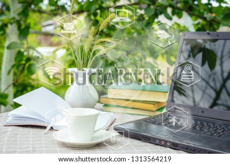 Digital learning, e-learning training. A computer, a cup of coffee is on the table in nature, on a summer day