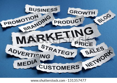 Marketing concept torn newspaper headlines reading marketing, strategy, branding, advertising etc