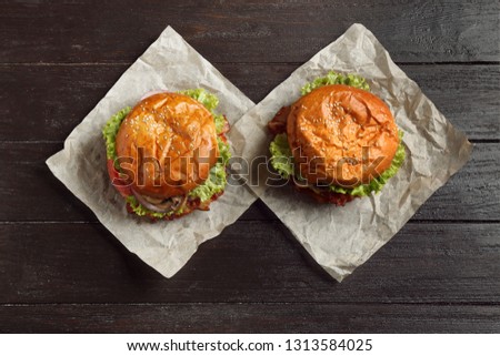 Delicious burgers with bacon on wooden table, top view