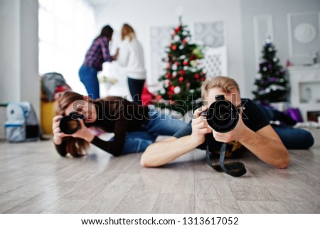 The team of two photographers lie on the floor and shooting on studio.