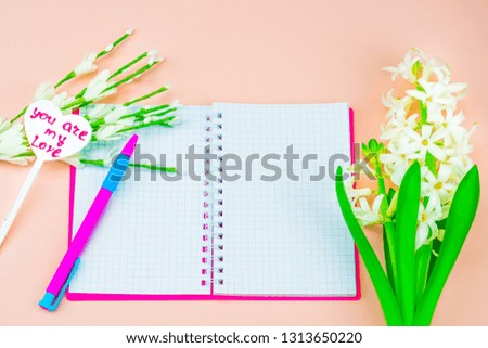 Spring in the working environment. Concept of women's day celebration. Notepad with pen, near a vintage heart with a signature. Pink background, March 8, still life