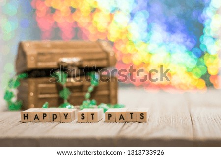 Happy St. Patrick's Day fun rainbow background on wooden board with treasure chest and shamrock and gold coins, selective focus, shallow DOF