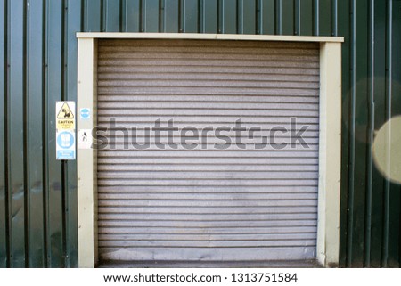 Roller door trades entrance garage door with warning / health and safety signs