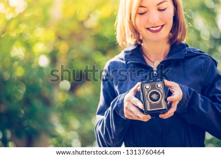 Cute girl is making pictures with a vintage camera, outside