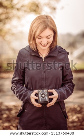 Cute girl is making pictures with a vintage camera, outside