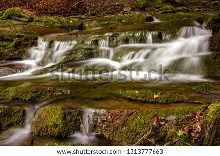 Close view of small cascade waterfall in a mountain river with rocks in the forest