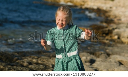 Emotional portrait of a funny and funny little blonde woman with a twisting head with laughing pigtails flying in the air while relaxing at sea with mom. Summertime. Summer vacation. Positive emotions