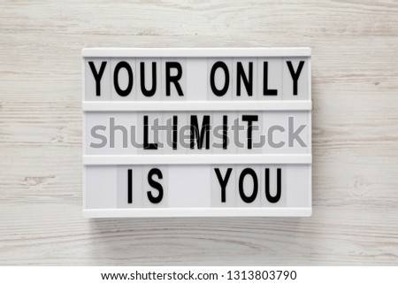 'Your only limit is you' word on lightbox on a white wooden background, top view. From above, flat lay, overhead. 