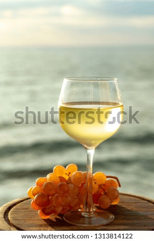 Aperitif cold white wine served in glasses with pink grapes on outdoor tessace witn sea view close up