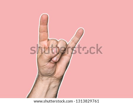 Man hand showing the Rock and Roll sign. Magazine style collage with copy space. Abstract creative background in coral color