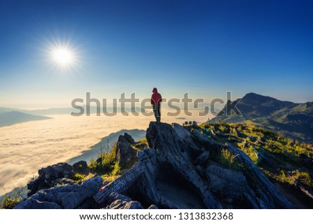 Traveler standing on the rock. Doi pha tang mountains and morning fog in Chiang rai, Thailand.