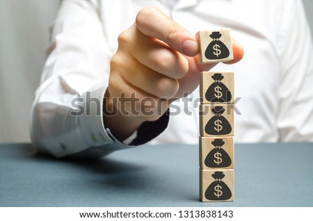Businessman puts a block with a picture of dollars. Increased budget and profits in the team. The capital accumulation and successful business.Increase investment fund. Saving money. Economic boom
