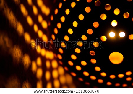 Coconut shell lamp with holes casting spotty magic yellow golden light pattern on the wall