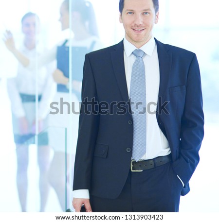 Portrait of young businessman in office with colleagues in the background . Portrait of young businessman.
