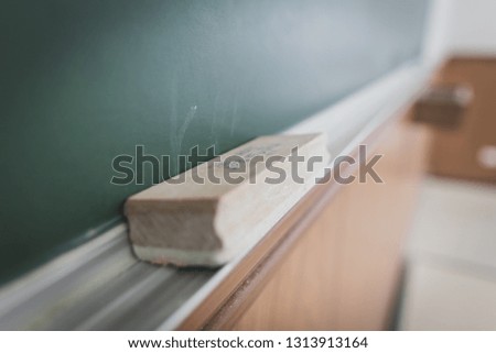 Close up of blackboard eraser on the metal storage rail on the bottom of the board
