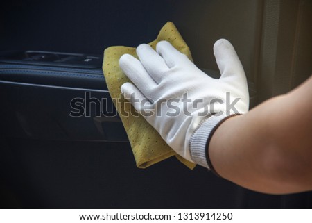This image is a picture of wiping the car by a yellow microfiber cloth with hand wearing gloves.Car wash concept.