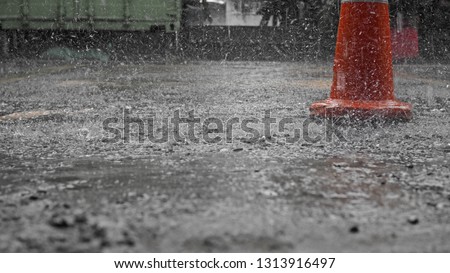 Heavy rain fall in a construction site. Focus on the orange color cone.