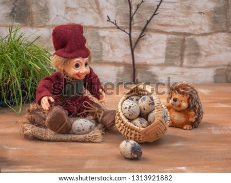 Fabulous picture with small toys. Hedgehog and Lesovik rest in the forest. They carry a large basket of quail eggs.