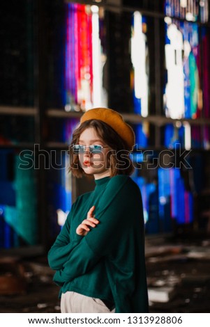 Side view portrait of serious curly girl in blue sunglasses, windows with colorful mosaic on background