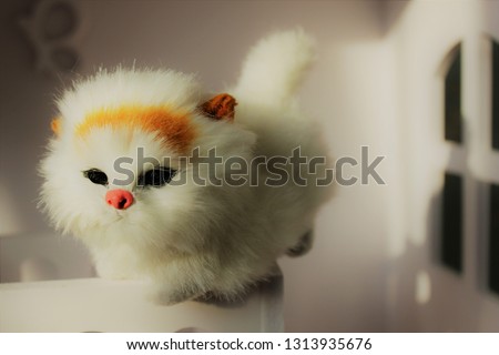 A small toy white kitten sits on a toy white cot in a children's house. Shabby Chic Style  in the interior of the children's room.