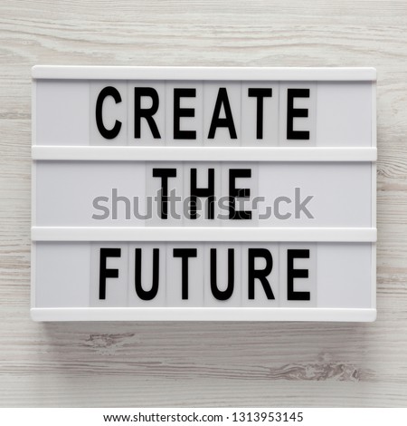 'Create the future' word on lightbox on a white wooden table, top view. From above, flat lay, overhead. 