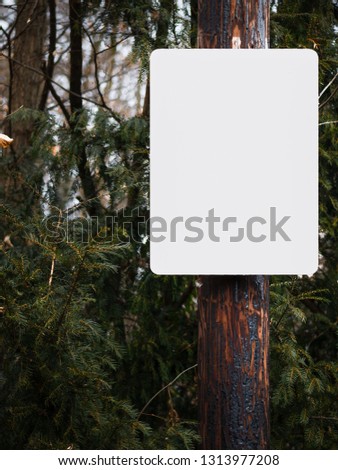 White sign with blanked space in nature to add text. Background with leafes and a tree on the right side.